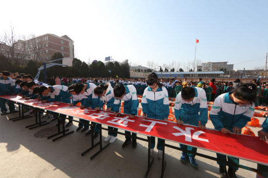 學(xué)生們?cè)凇八掀桨步煌ǎ踩槲页砷L(zhǎng)”的橫幅上簽字