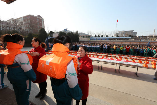 客船服務(wù)員向?qū)W生演示救生衣穿戴